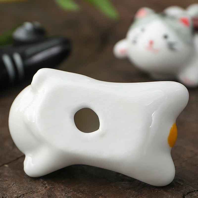 White ceramic kawaii cat-shaped object on a wooden surface with blurred background