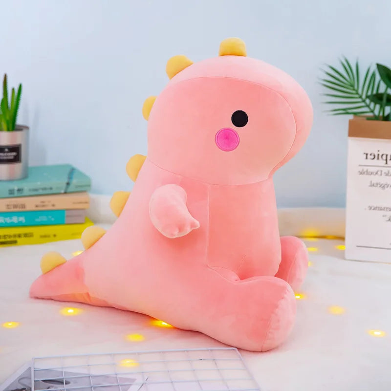 Pink dinosaur kawaii plush toy on a light surface with books and plants in the background