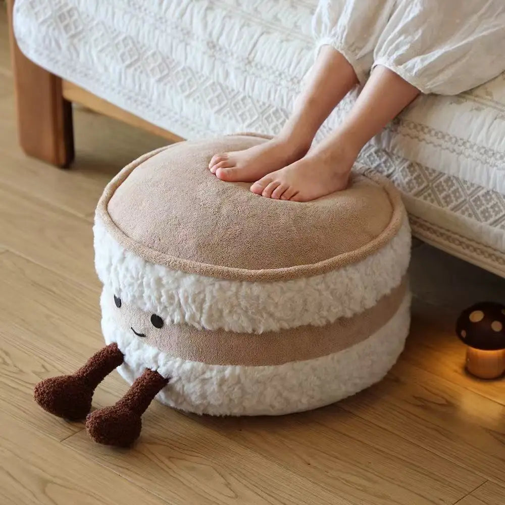 Round kawaii cushion with a face design on a wooden floor, with a person sitting on it.