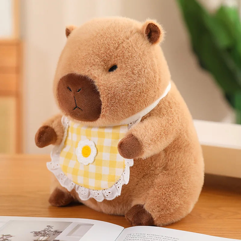 Kawaii plush toy animal wearing a yellow checkered dress with a flower on a wooden surface.