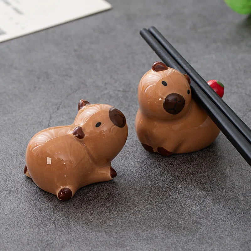 Two brown ceramic kawaii animal-shaped chopstick holders on a gray surface.