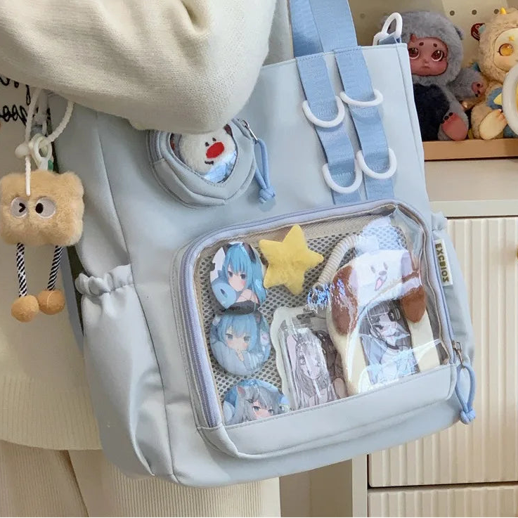 Light blue Kawaii backpack with various items and charms, held by a person.