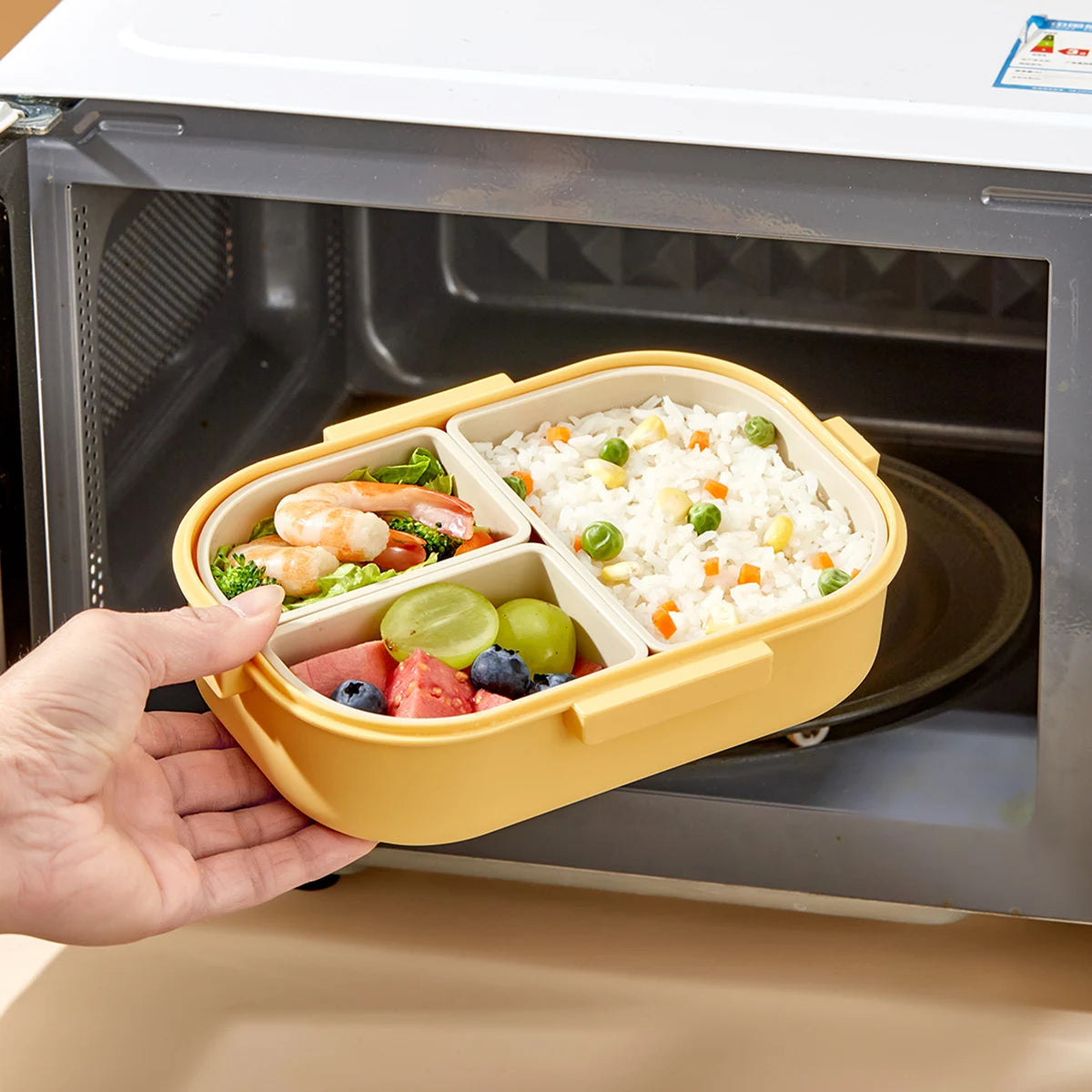 Yellow kawaii bento box with food being placed into a microwave