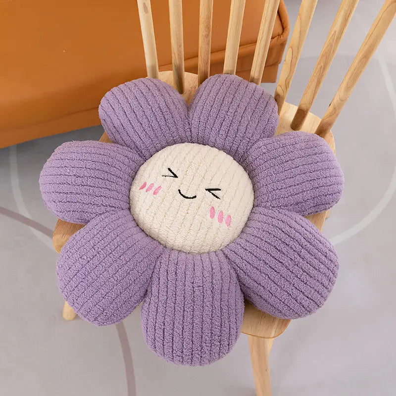 Flower-shaped kawaii pillow with a smiling face on a wooden chair.
