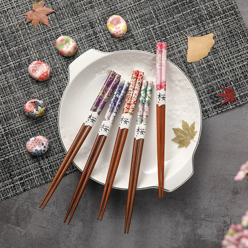 Set of floral-patterned kawaii chopsticks on a decorative plate with a textured gray background.