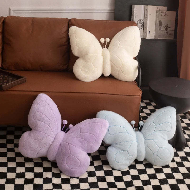 Butterfly-shaped kawaii cushions in various colors on a checkered floor with a brown sofa in the background.
