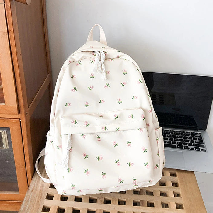 Kawaii floral-patterned backpack on a wooden surface next to a laptop