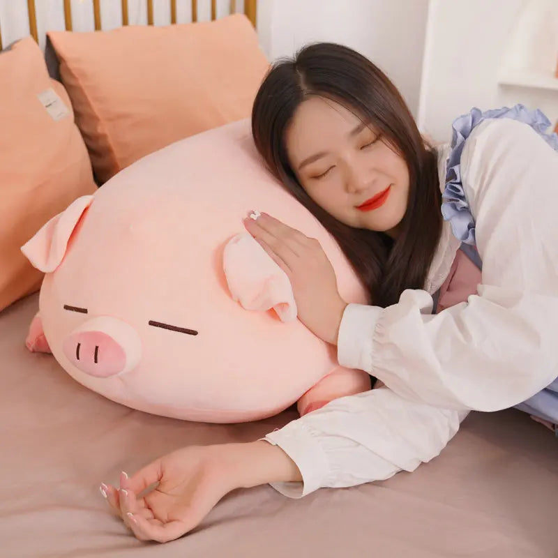 Woman hugging a large pink pig-shaped kawaii pillow on a bed.