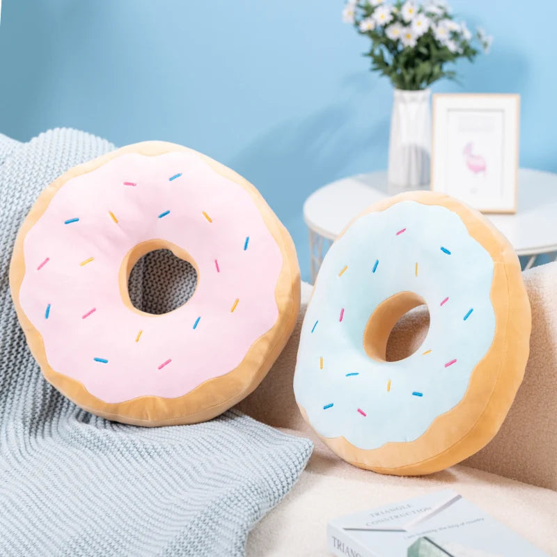 Two donut-shaped kawaii cushions with pink and blue icing on a light blue background.