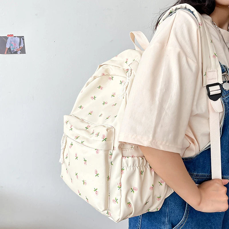 Person wearing a light-colored Kawaii backpack with floral patterns on a plain background