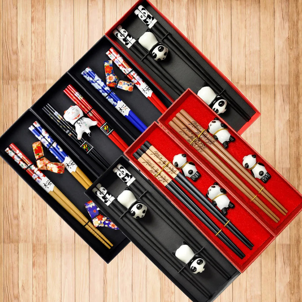 Set of chopsticks with kawaii panda designs in a red and black box on a wooden surface