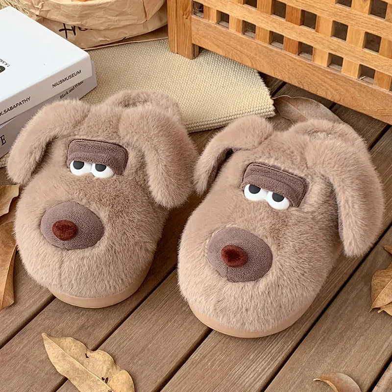 Pair of dog-shaped kawaii slippers on a wooden floor with books and a basket in the background.