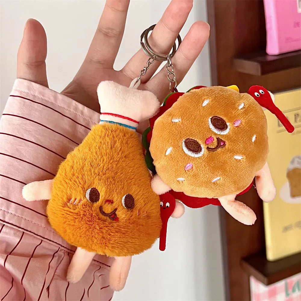 Plush keychains shaped like a kawaii fried chicken drumstick and a hamburger held by a hand.