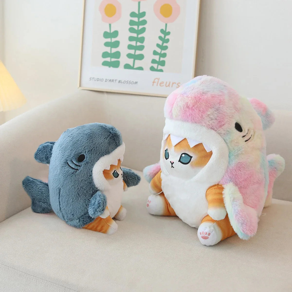Two kawaii plush toys, one shark and one cat-like creature with a colorful shell, on a light-colored surface.