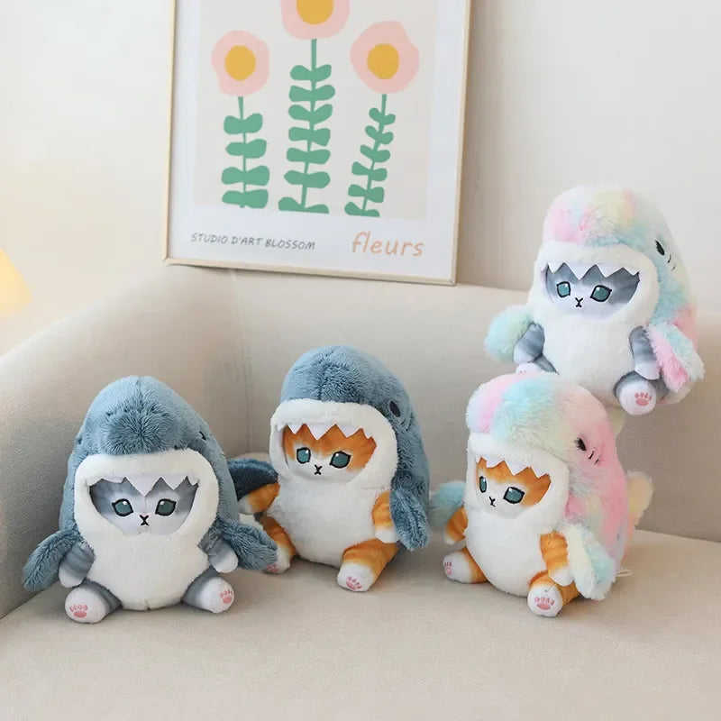 Set of four colorful plush toys resembling sharks on a light-colored surface with a kawaii floral painting in the background.