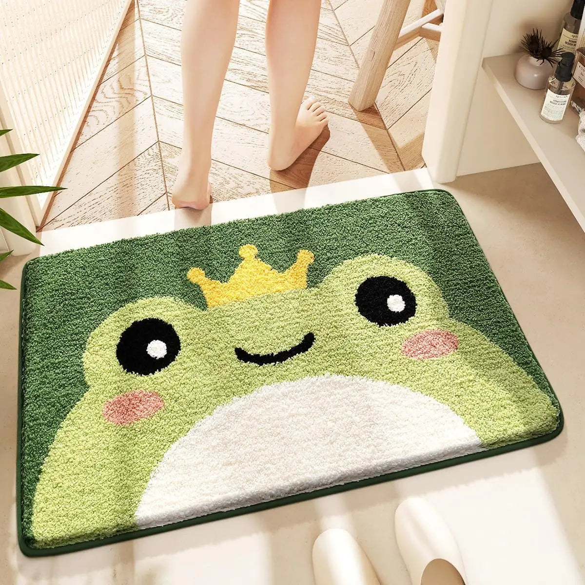 Kawaii frog-shaped doormat with a crown on a floor, with a person stepping onto it.