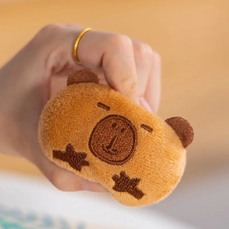 Kawaii plush toy shaped like a bear with a smiling face held by a hand against a blurred background