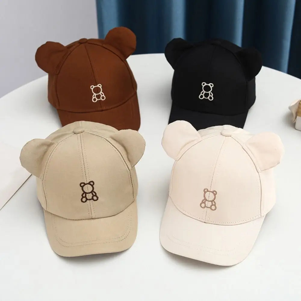 Four Kawaii bear-ear hats in brown, black, beige, and white on a white surface.