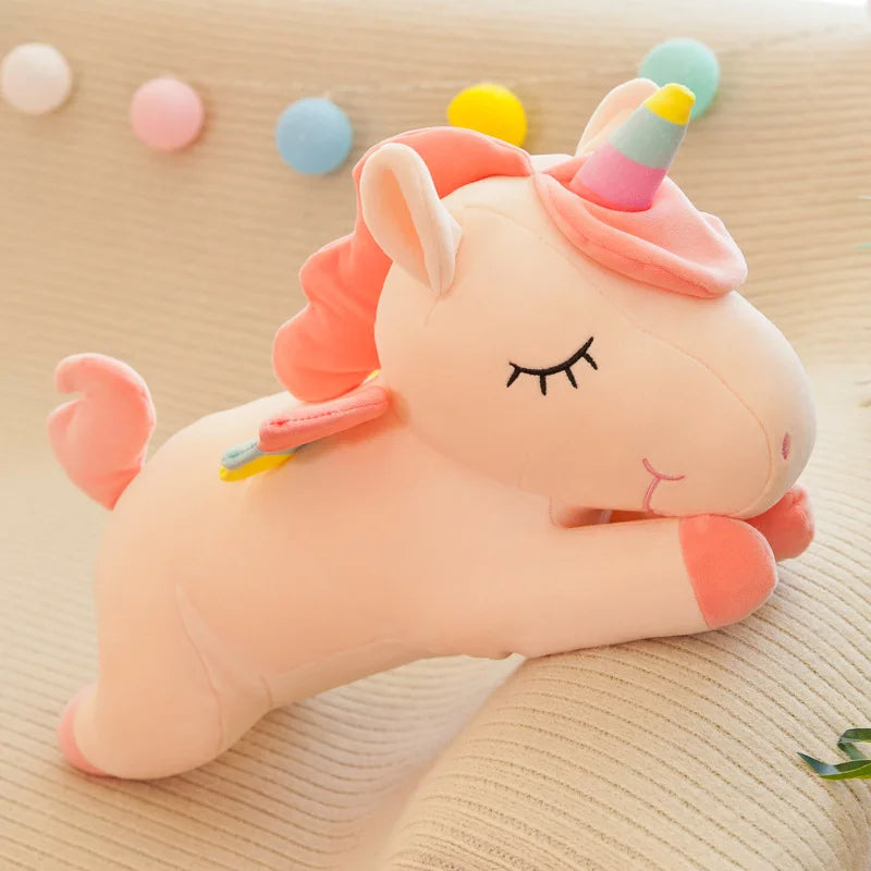 Pink unicorn plush kawaii toy with a rainbow horn on a beige surface