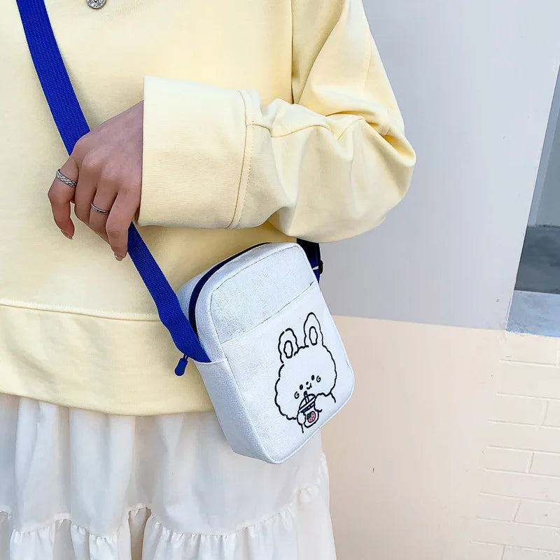 Person wearing a yellow sweatshirt with a white crossbody bag featuring a Kawaii cartoon character design.