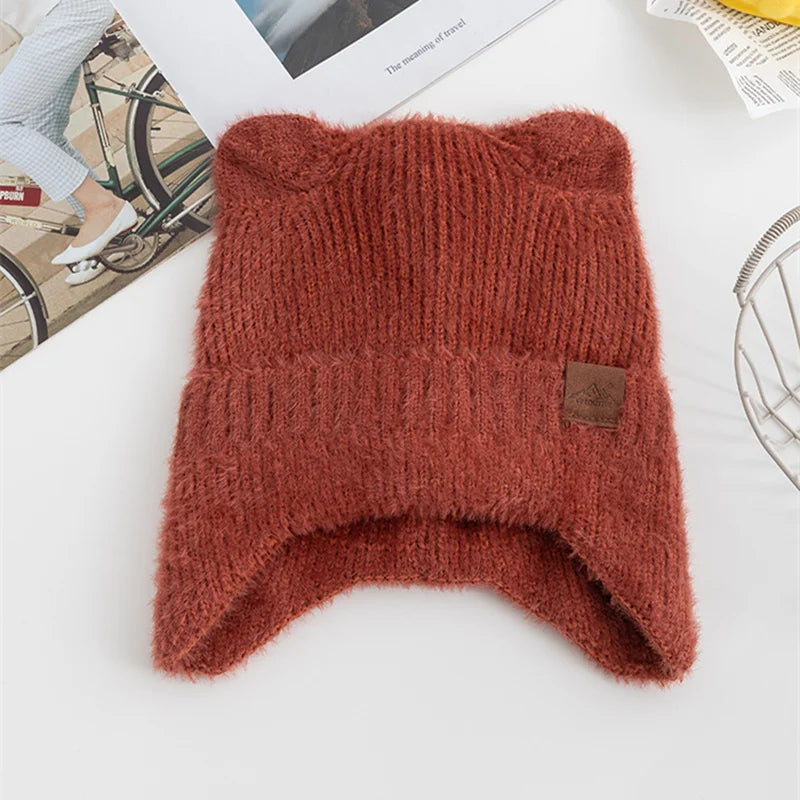 Brown knitted Kawaii hat with a brand tag on a white surface