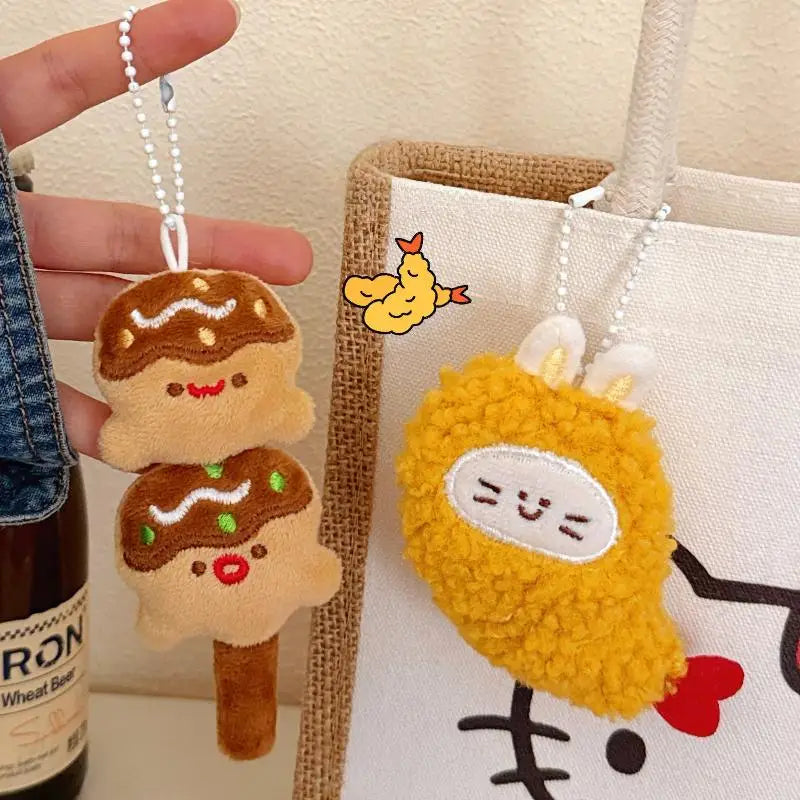 Two kawaii plush keychains, one resembling a ice cream cone and the other a yellow creature, hanging from strings.