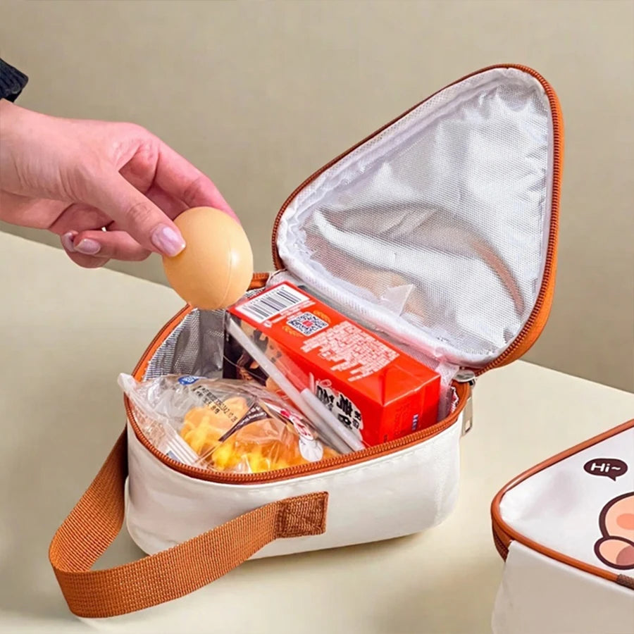 Hand reaching into a small kawaii-inspired insulated cooler bag with food items on a beige background