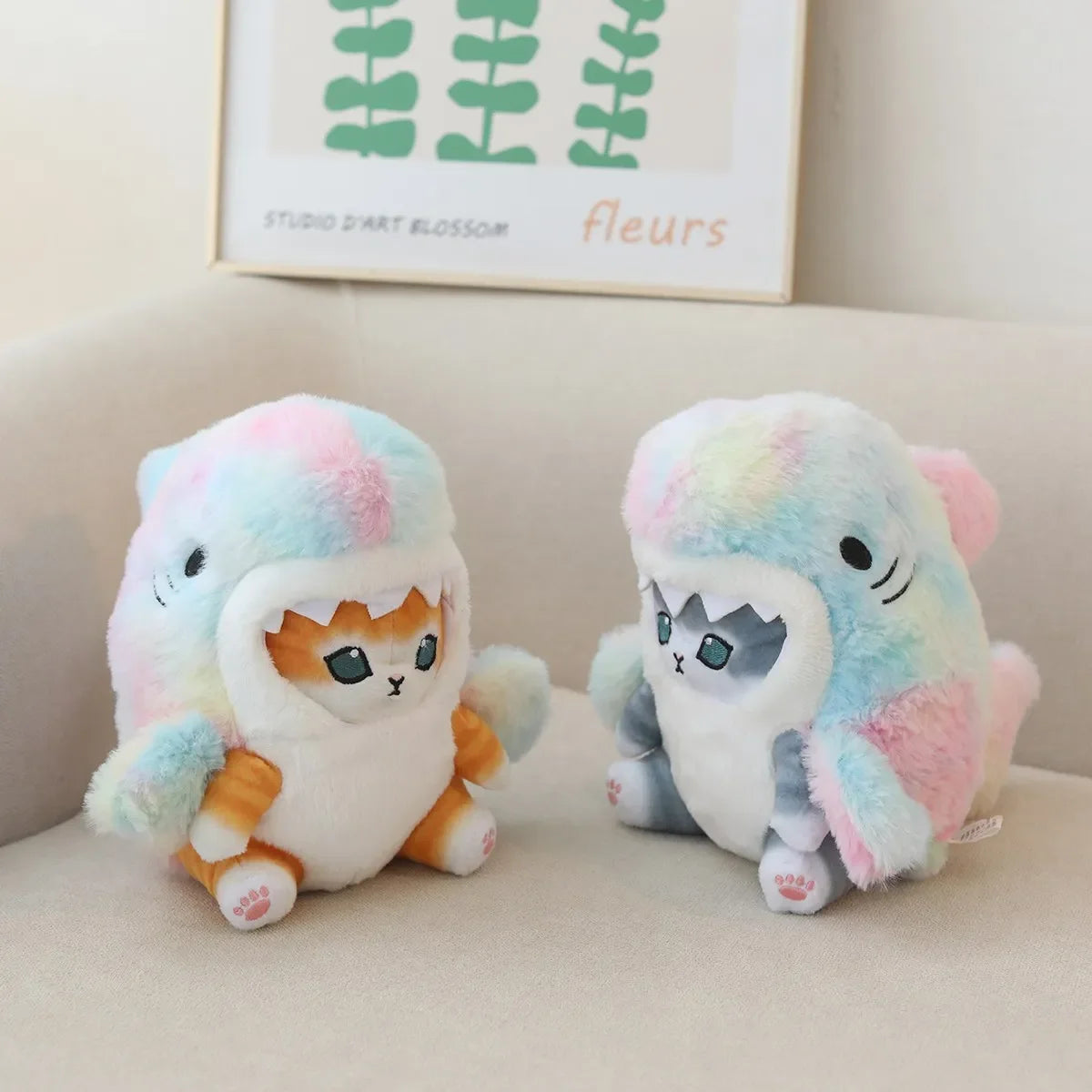Two colorful kawaii plush toys resembling a cat and a dog on a light-colored surface with a framed picture in the background.