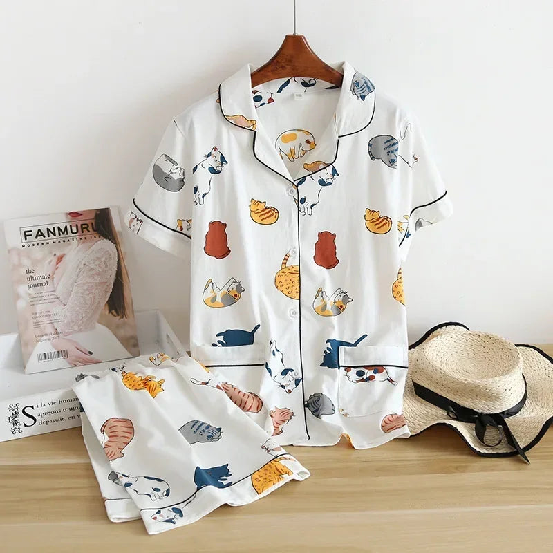 White pajama set with kawaii animal prints on a wooden surface with a hat and magazine in the background.