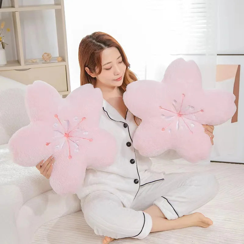 Woman holding large pink Kawaii flower-shaped cushions in a bright room.