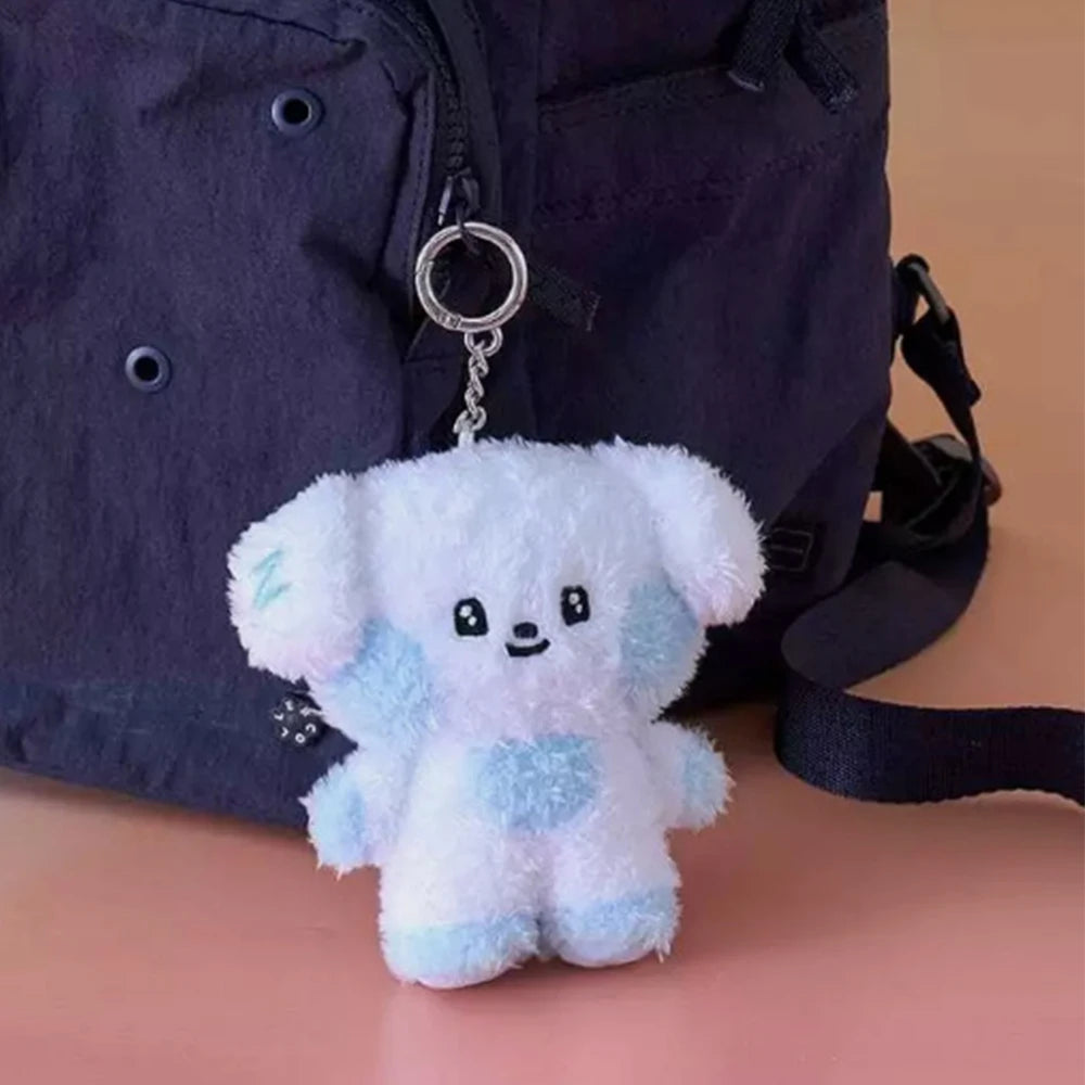 Plush kawaii dog-shaped kawaii keychain attached to a dark blue backpack on a beige surface