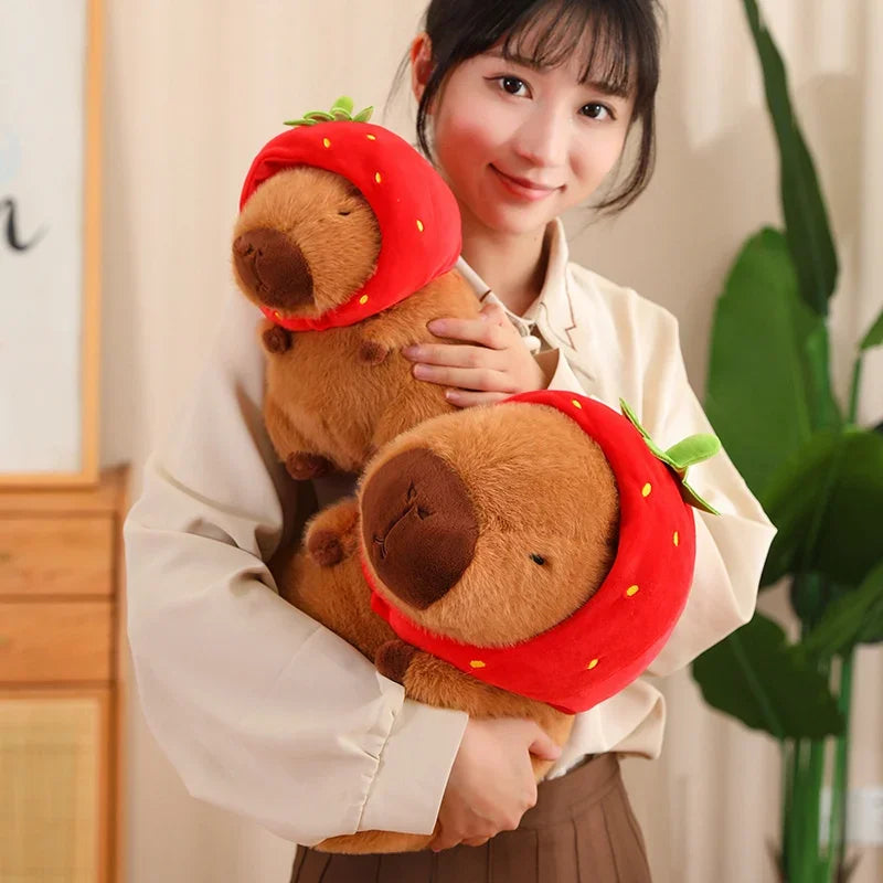 Person holding two kawaii plush toys resembling beavers with strawberry hats.