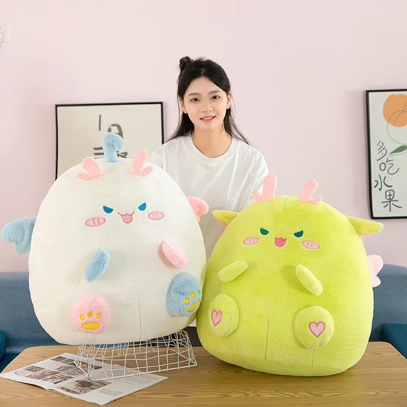 Person holding two colorful kawaii plush toys on a table with a light pink wall in the background