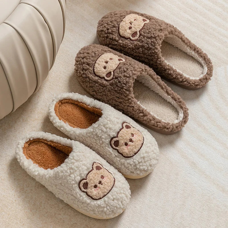 Pair of plush slippers with kawaii bear face designs on a soft surface