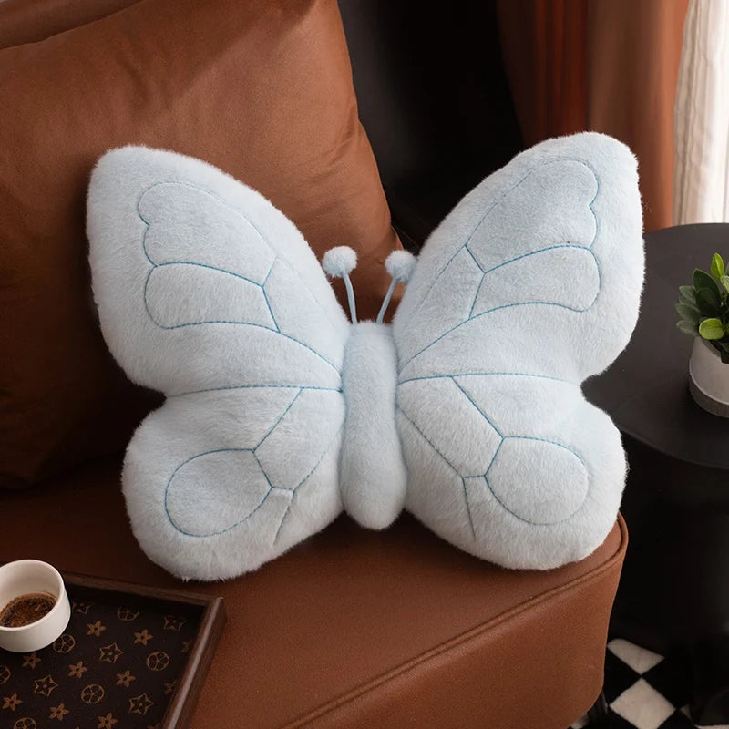 Plush butterfly kawaii pillow on a brown couch with a blurred background