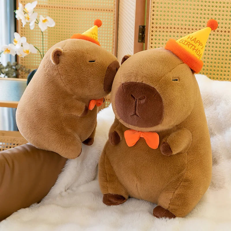Two kawaii plush beavers wearing party hats and bow ties on a white surface.