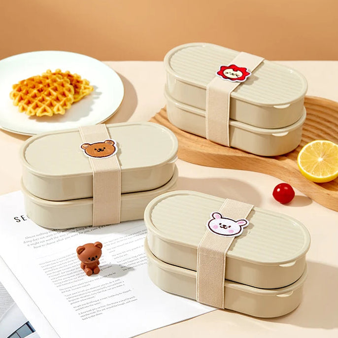 Three beige bento boxes with kawaii bear and flower designs on a wooden surface with food items.