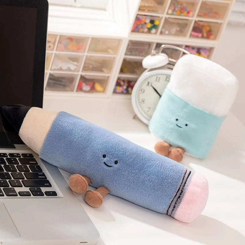 Two kawaii plushies with smiling faces on a desk next to a laptop and clock.