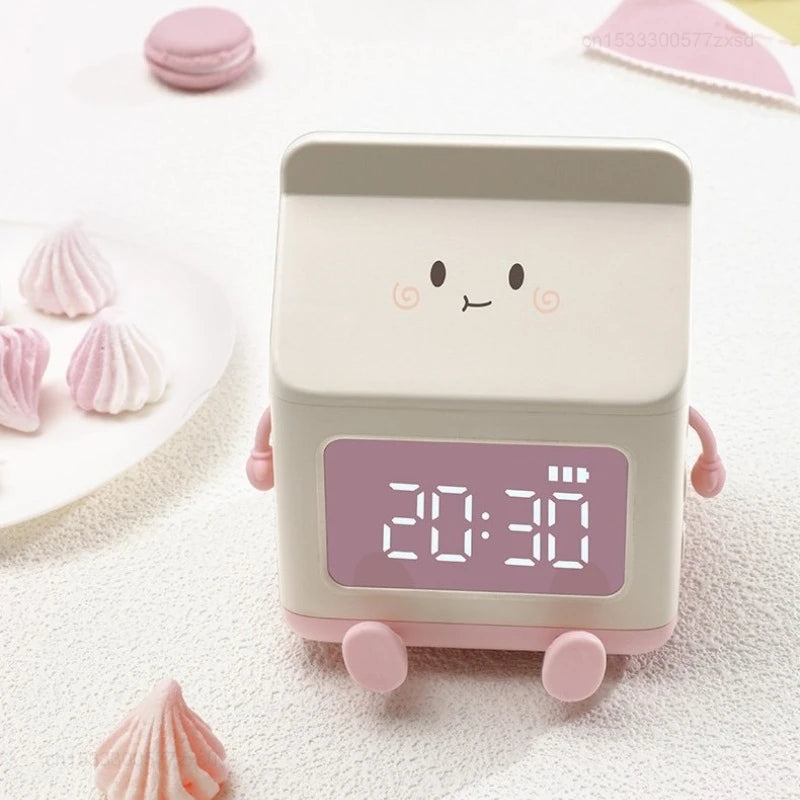 Cute kawaii digital clock with a smiling face on a white surface with pink decorative items.