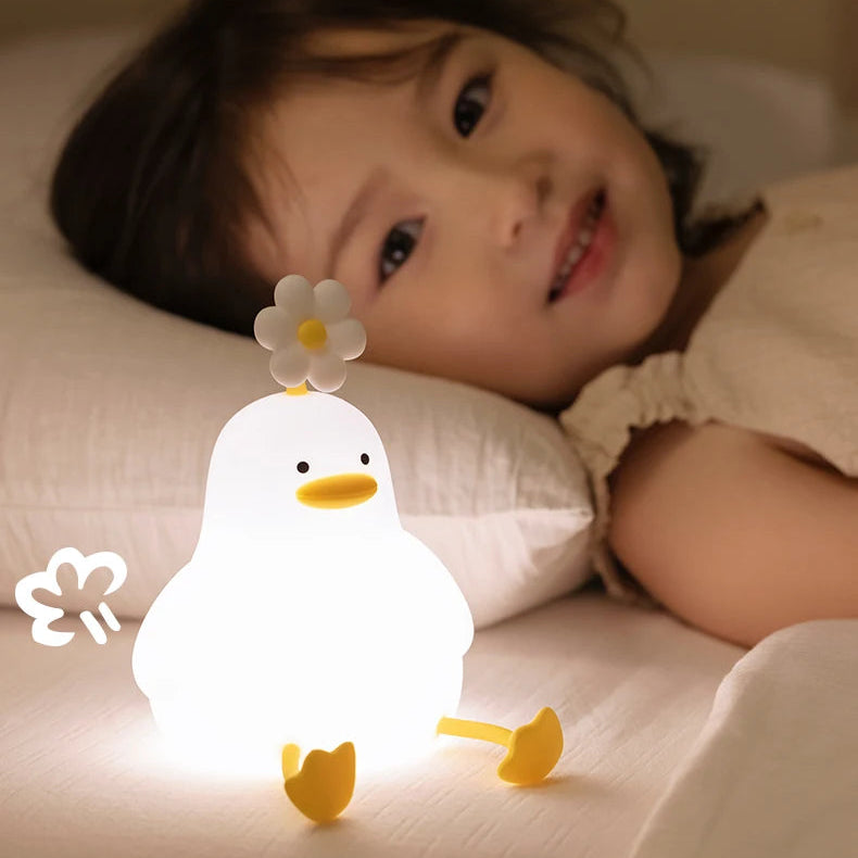 Child lying on a bed with a cute duck-shaped kawaii night light next to them