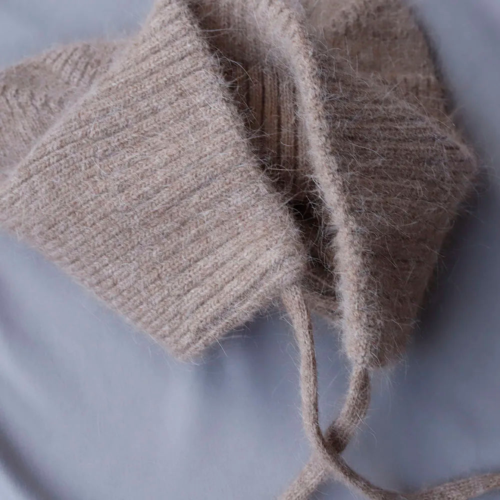 Close-up of beige knitted Kawaii hat on a light gray background