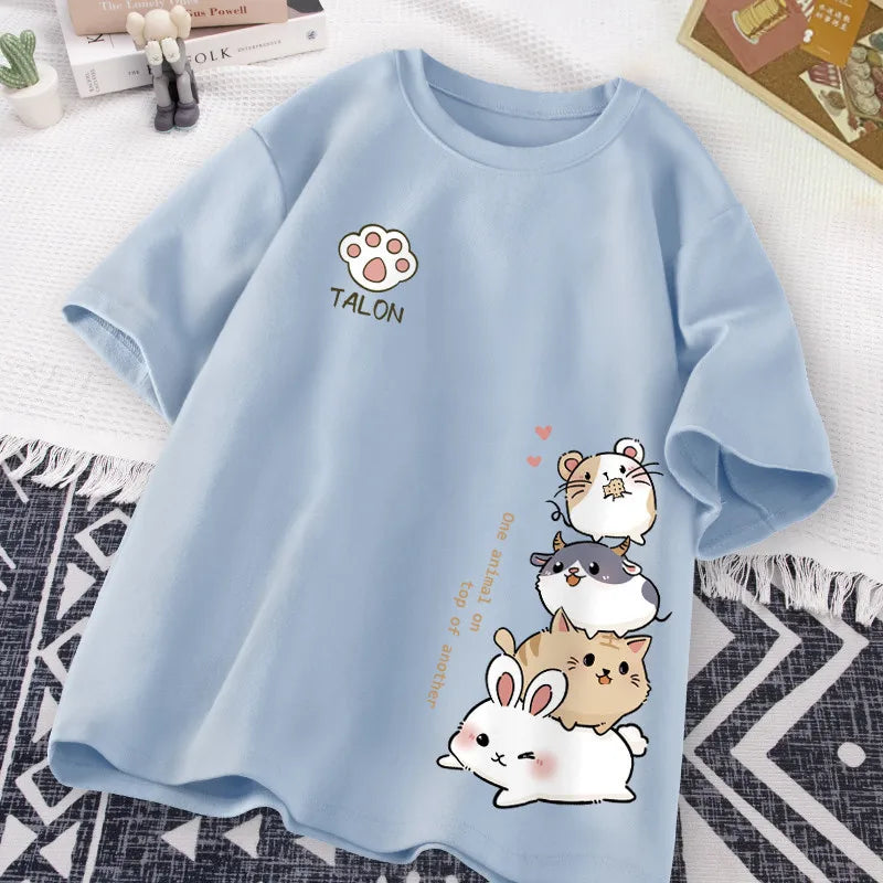 Light blue t-shirt with kawaii cartoon animals and 'TALON' branding on a patterned surface.