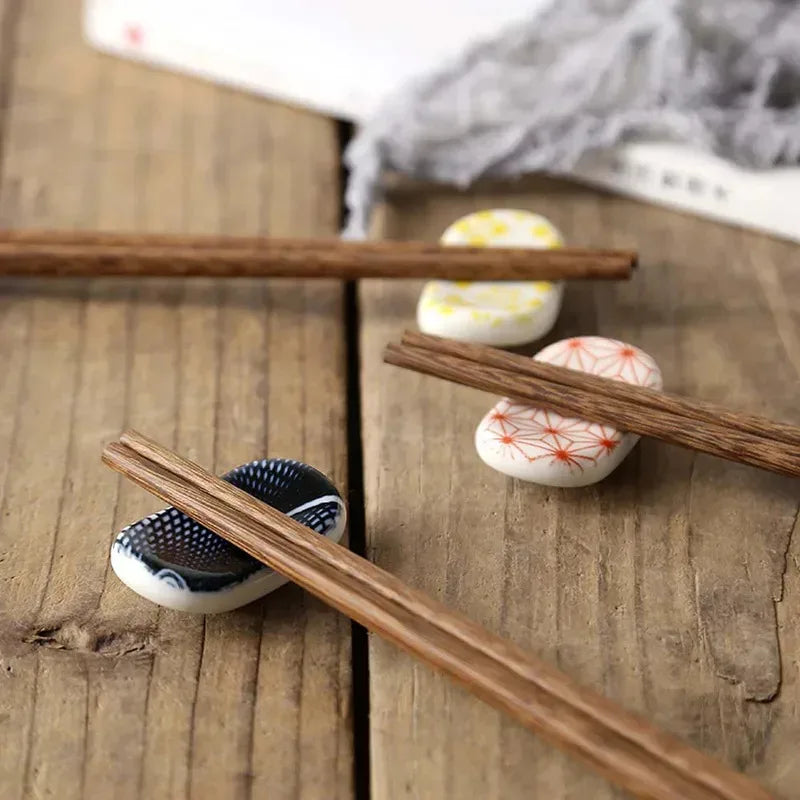 Chopsticks resting on ceramic holders with kawaii decorative patterns on a wooden surface.