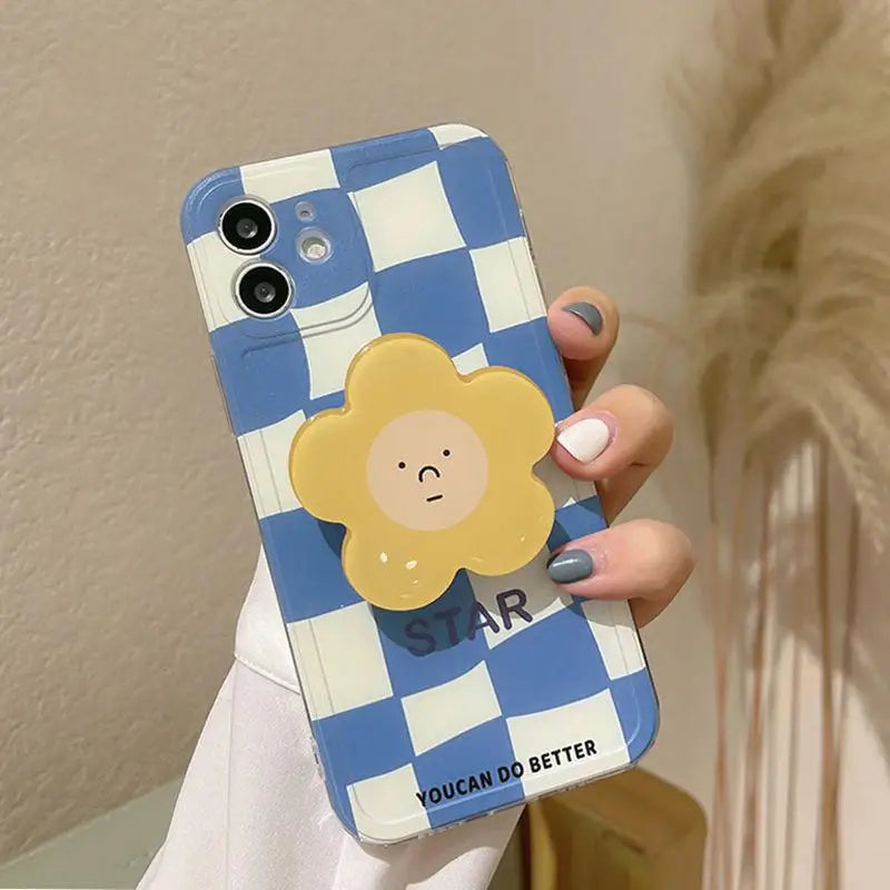 Phone case with blue and white checkered kawaii pattern and cartoon sun design held by a person.