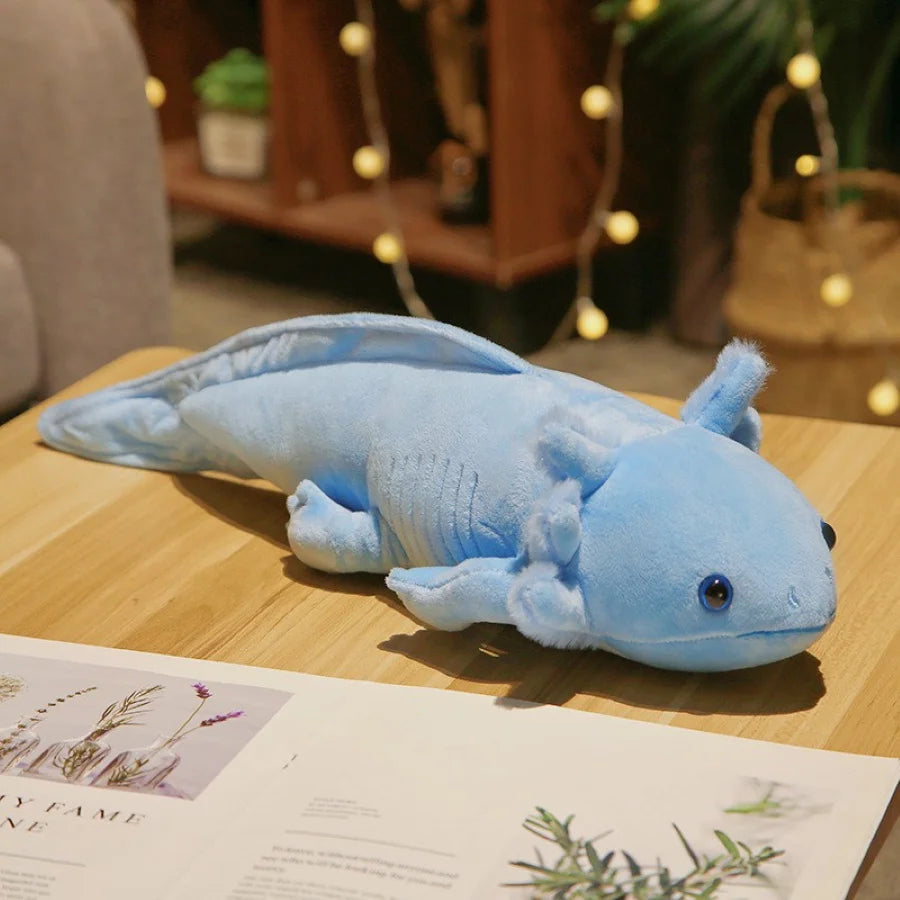 Blue axolotl kawaii plush toy on a wooden surface with a blurred indoor background