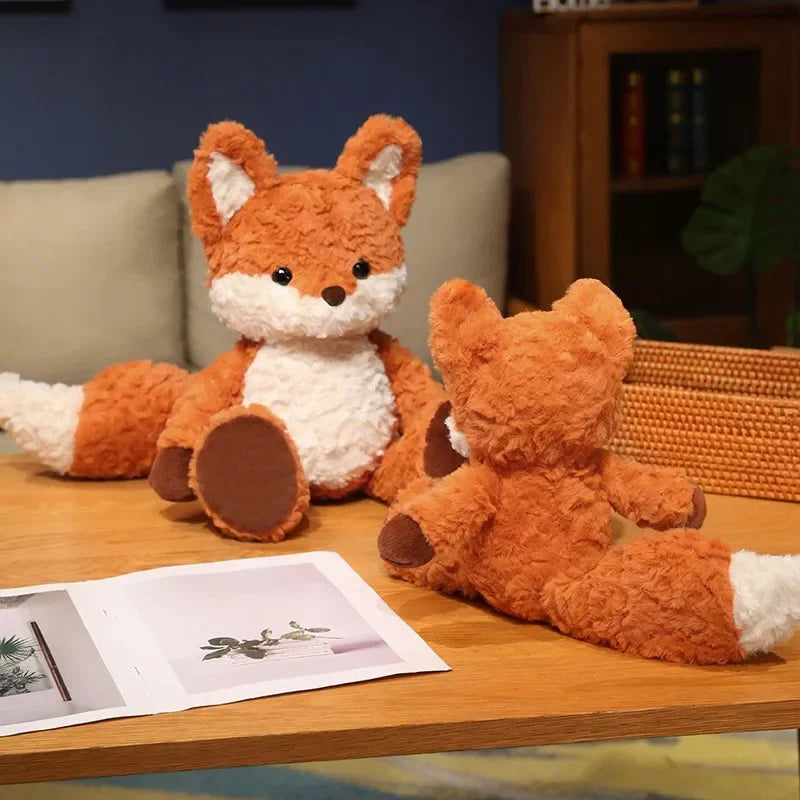 Two plush kawaii fox toys on a wooden surface with a magazine underneath.