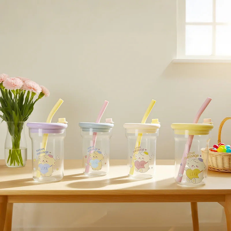Four children's cups with straws on a wooden table, with Kawaii flowers and a basket in the background.