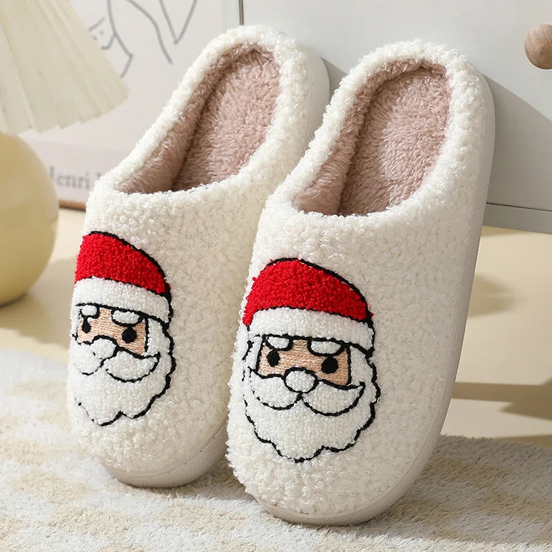 Pair of white slippers with kawaii Santa Claus face design on a soft surface.