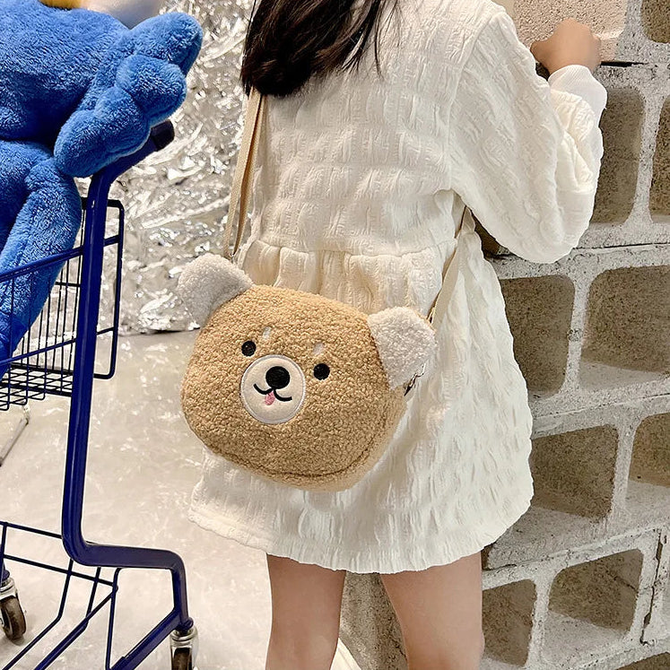 Person holding a Kawaii bear-shaped plush bag next to a blue shopping cart against a brick wall.