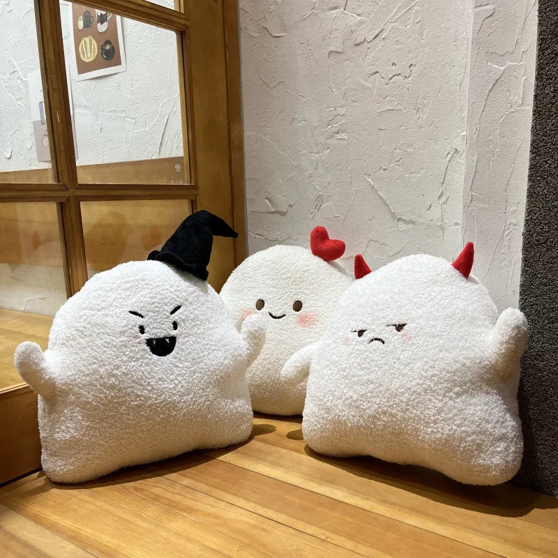 Three cartoonish ghost kawaii plush toys with different expressions on a wooden floor.